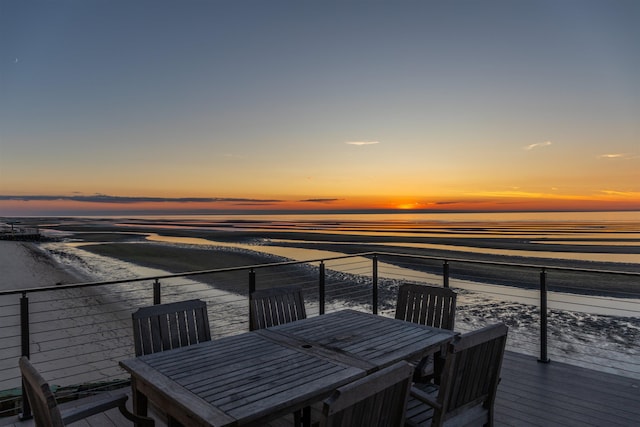 deck at dusk featuring a water view