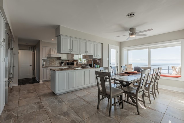 dining area featuring ceiling fan and a water view