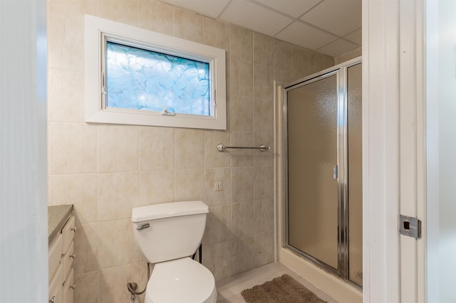 bathroom with tile walls, vanity, an enclosed shower, and toilet