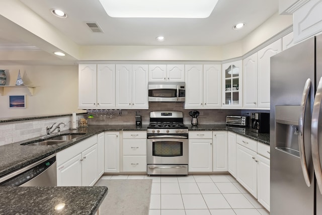 kitchen featuring appliances with stainless steel finishes, sink, white cabinets, and dark stone counters