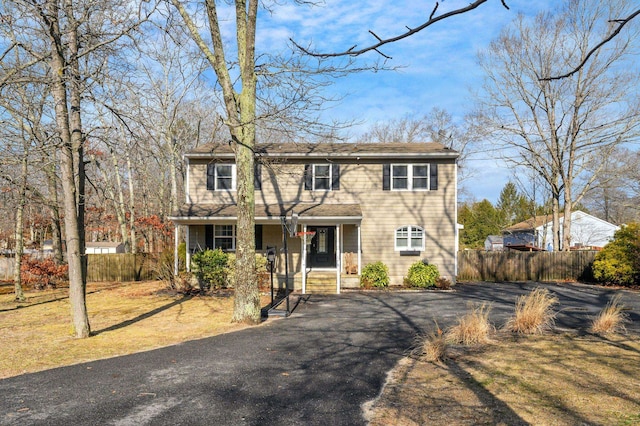 view of front of property with aphalt driveway, a porch, and fence