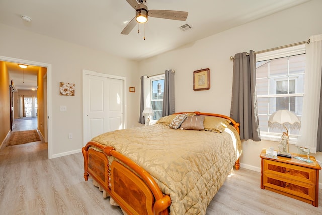 bedroom with light wood finished floors, baseboards, visible vents, and a closet