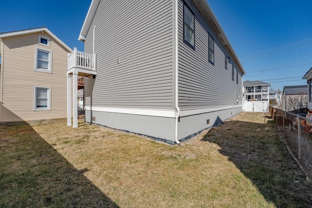 view of property exterior featuring crawl space, a balcony, fence, and a lawn