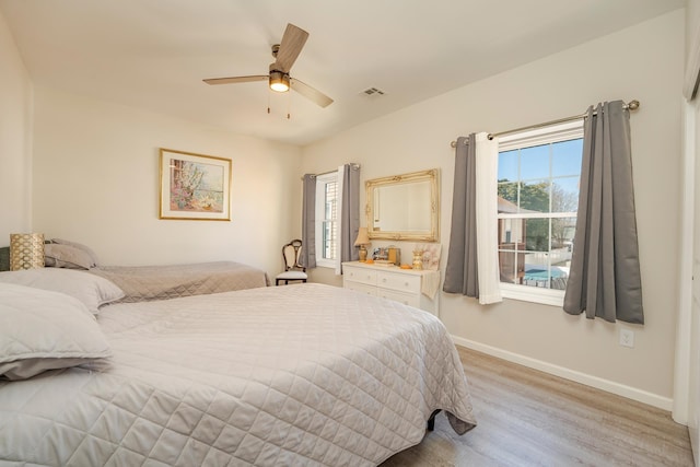 bedroom featuring light wood-type flooring, baseboards, multiple windows, and visible vents