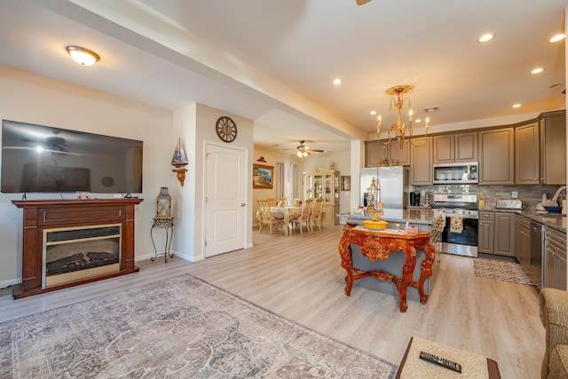 kitchen with appliances with stainless steel finishes, a center island, light wood-type flooring, and decorative backsplash