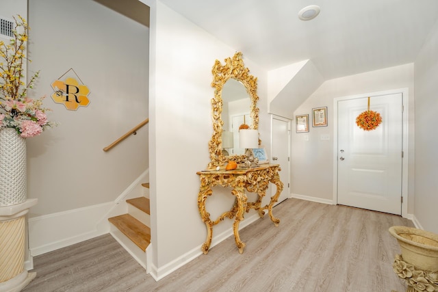 foyer with baseboards, stairway, and light wood finished floors