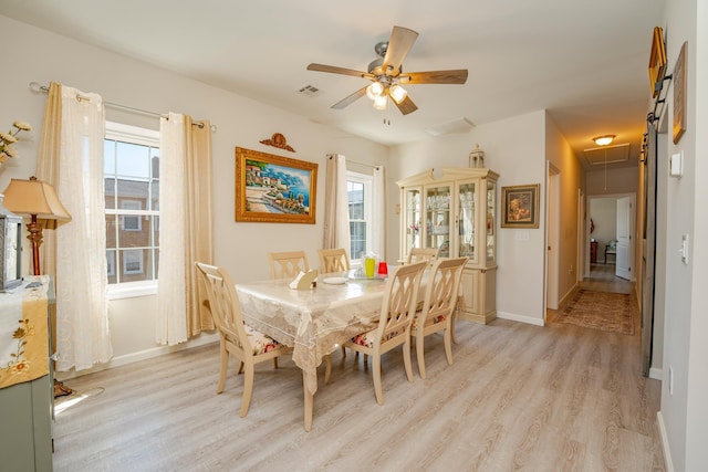 dining space featuring light wood finished floors, attic access, visible vents, and baseboards