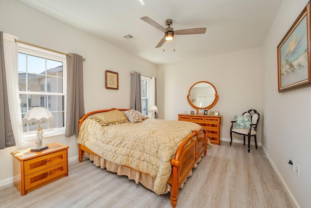 bedroom with light wood-style flooring, a ceiling fan, visible vents, and baseboards