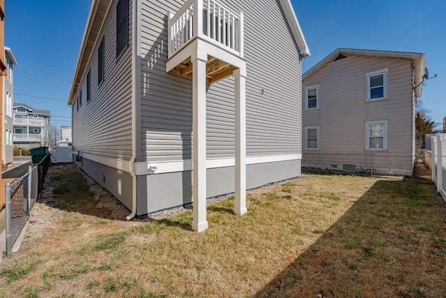 view of side of home featuring a lawn, crawl space, a balcony, cooling unit, and a fenced backyard