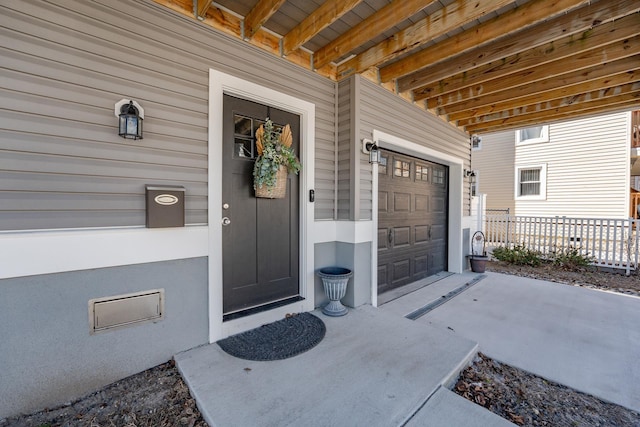 view of exterior entry with a garage and fence