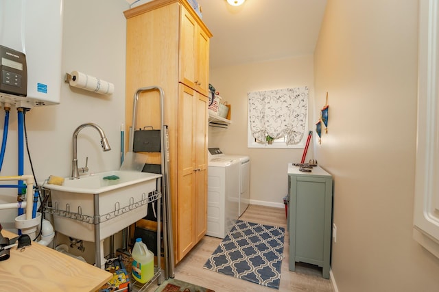 laundry room with a sink, baseboards, light wood-style floors, independent washer and dryer, and cabinet space