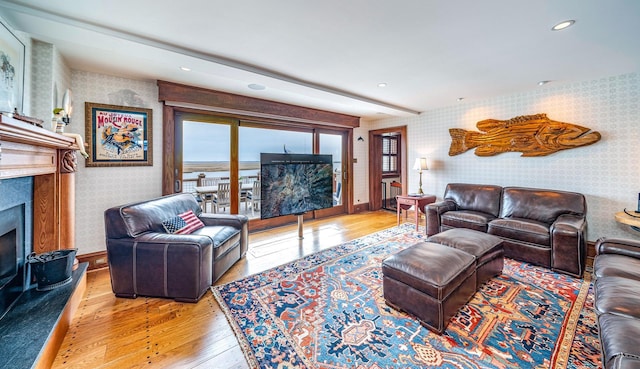 living room with a fireplace, light hardwood / wood-style flooring, and beamed ceiling