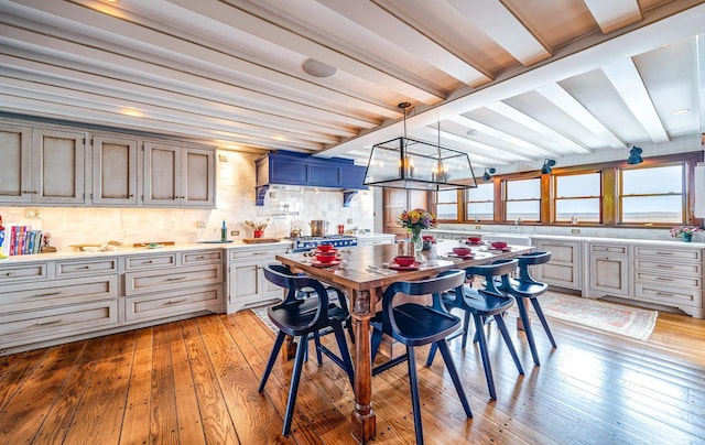 dining room featuring a notable chandelier, beam ceiling, and light wood-type flooring
