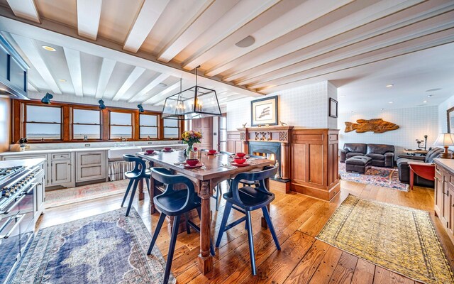 dining area with beam ceiling, light hardwood / wood-style flooring, and a chandelier