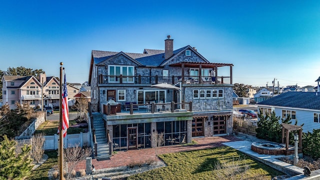 back of house featuring a lawn, a fire pit, and a balcony