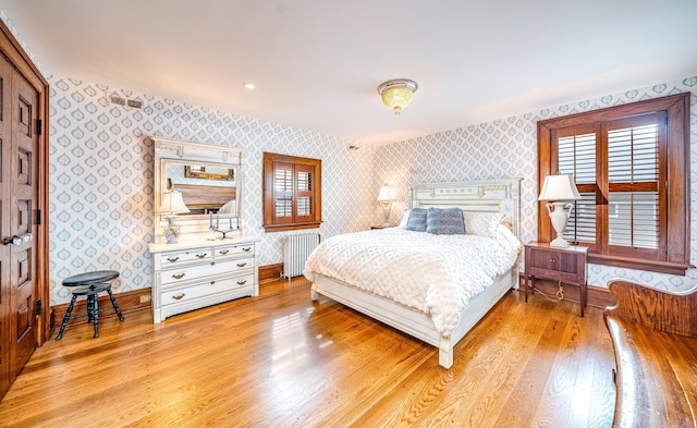bedroom with radiator heating unit and light hardwood / wood-style floors