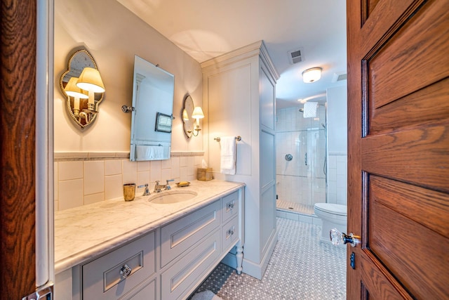 bathroom featuring walk in shower, tile patterned floors, toilet, vanity, and tile walls