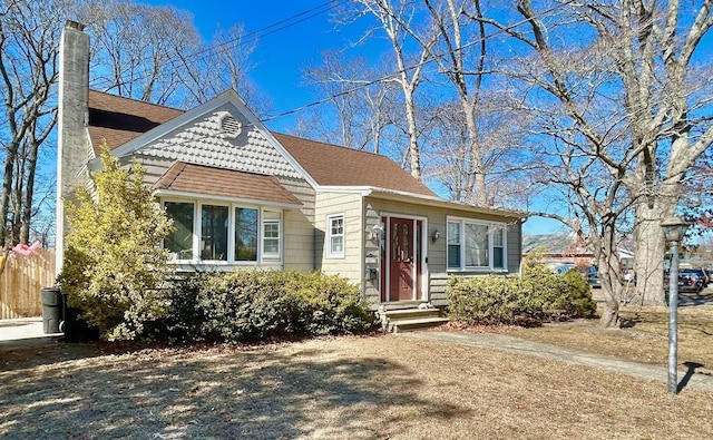 view of front facade featuring a shingled roof and a chimney