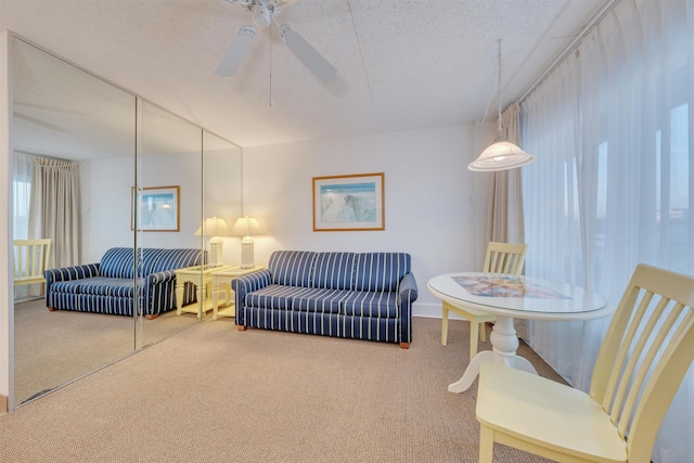 carpeted living room featuring ceiling fan and a textured ceiling