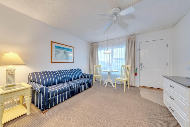 living room featuring ceiling fan, light colored carpet, and a textured ceiling