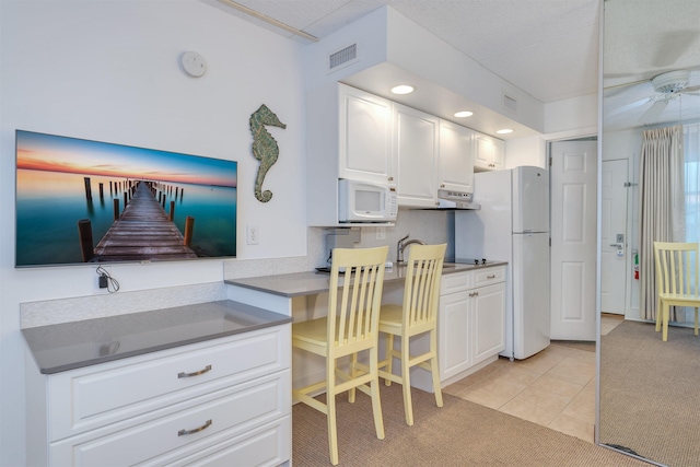 kitchen with ceiling fan, white appliances, white cabinetry, and light carpet