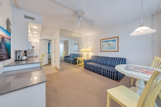 living room featuring ceiling fan, sink, a textured ceiling, and light carpet