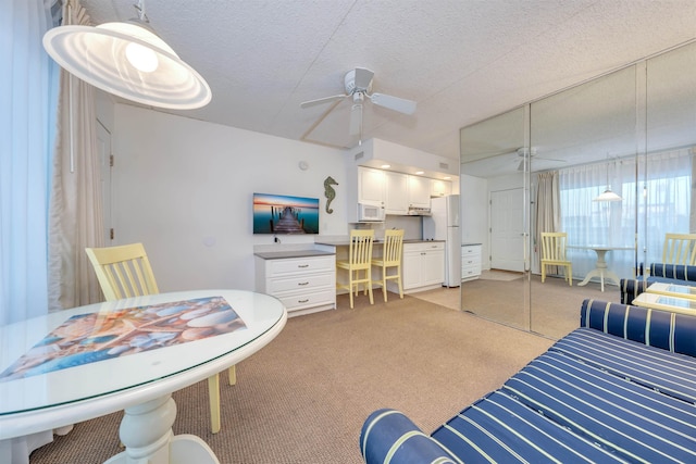 bedroom featuring white refrigerator, ceiling fan, a textured ceiling, light colored carpet, and a closet