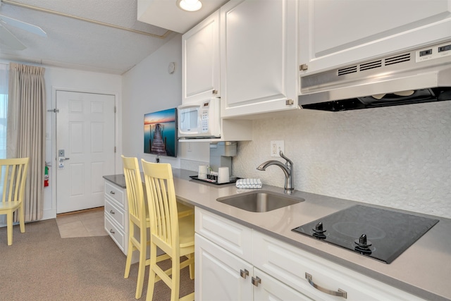 kitchen featuring black electric stovetop, tasteful backsplash, ventilation hood, sink, and white cabinets