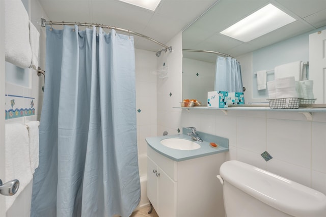 full bathroom with toilet, a paneled ceiling, decorative backsplash, vanity, and tile walls