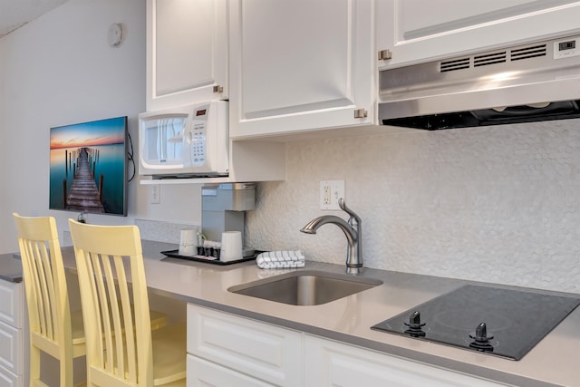 kitchen featuring black electric cooktop, sink, white cabinets, and range hood