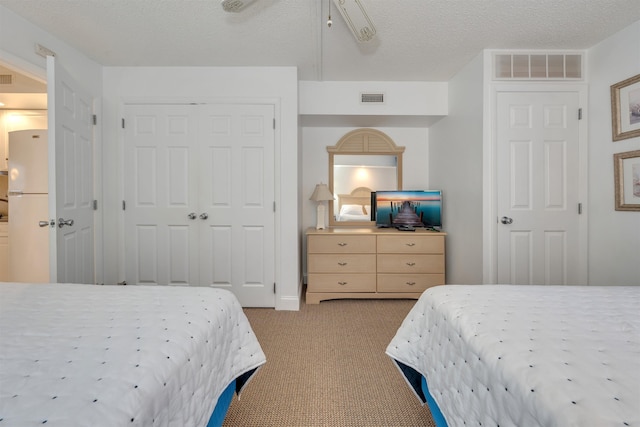 bedroom featuring ceiling fan, white refrigerator, light colored carpet, and a textured ceiling