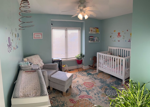 bedroom featuring ceiling fan and a crib