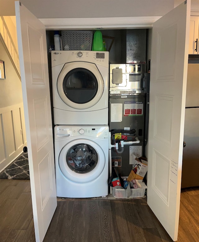 laundry area with dark hardwood / wood-style flooring and stacked washer and clothes dryer