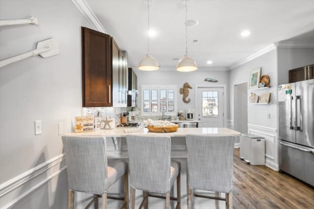 kitchen with a peninsula, freestanding refrigerator, light countertops, a kitchen bar, and backsplash