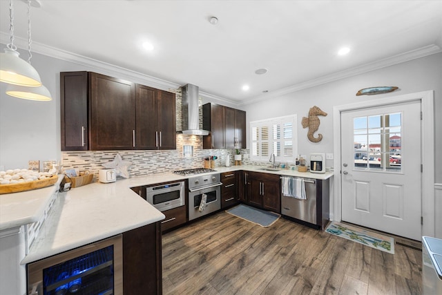 kitchen featuring a sink, wine cooler, dark brown cabinetry, appliances with stainless steel finishes, and wall chimney exhaust hood