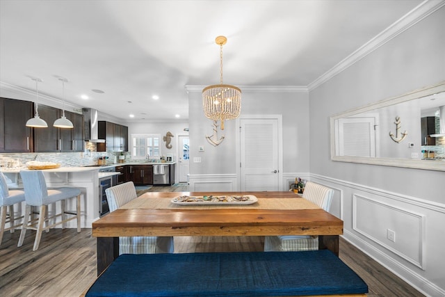 dining space with dark wood-style floors, a notable chandelier, wainscoting, and ornamental molding