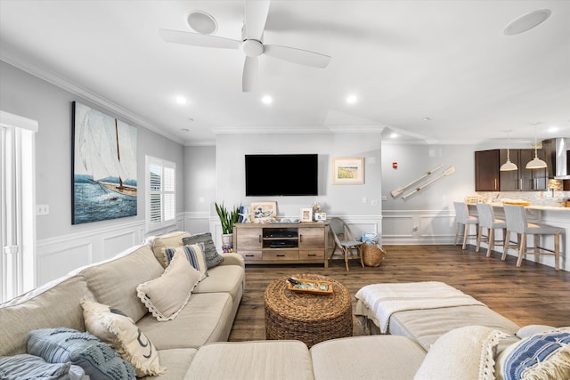 living room with ornamental molding, a ceiling fan, wood finished floors, recessed lighting, and wainscoting