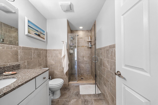 full bath with vanity, tile walls, toilet, and a shower stall