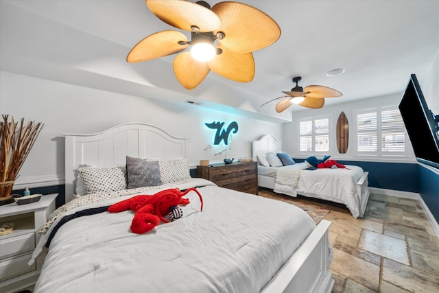 bedroom with a ceiling fan, baseboards, visible vents, and stone tile flooring