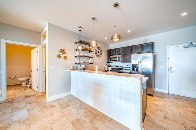 kitchen with appliances with stainless steel finishes, pendant lighting, a peninsula, light countertops, and open shelves