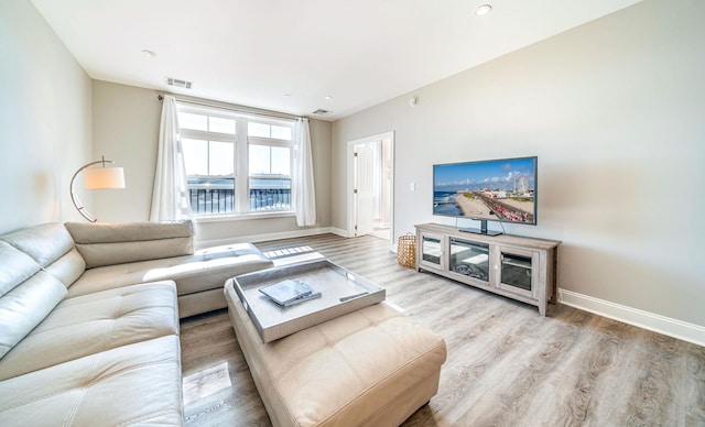 living room with wood finished floors, visible vents, and baseboards