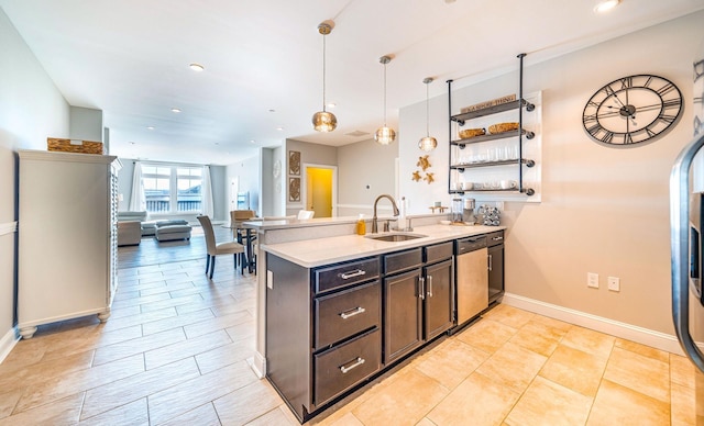 kitchen featuring open floor plan, decorative light fixtures, a sink, light countertops, and stainless steel dishwasher