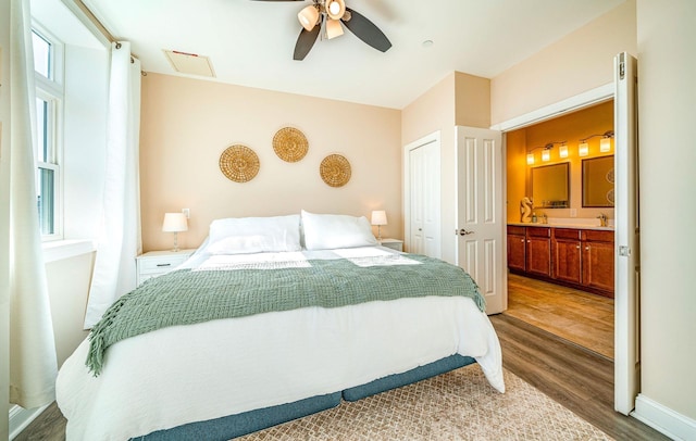 bedroom with ceiling fan, connected bathroom, wood finished floors, a closet, and attic access