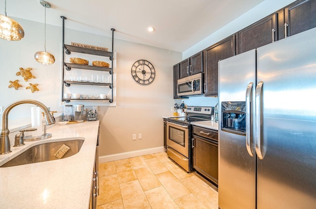 kitchen featuring pendant lighting, open shelves, stainless steel appliances, light countertops, and a sink