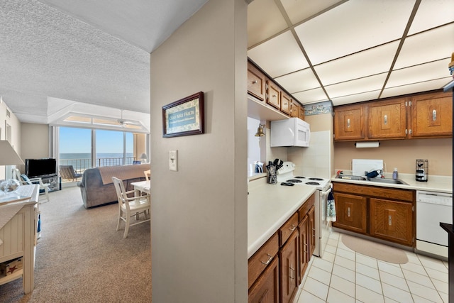 kitchen with white appliances, a textured ceiling, ceiling fan, sink, and light tile patterned floors