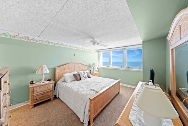 bedroom with a paneled ceiling, a water view, ceiling fan, and carpet floors