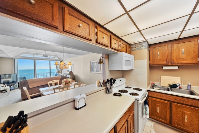 kitchen featuring sink, tasteful backsplash, white appliances, light tile patterned floors, and ceiling fan with notable chandelier