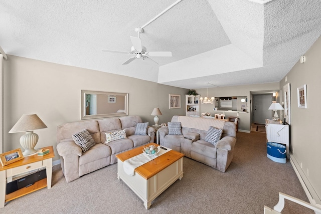 living room with a raised ceiling, ceiling fan, light carpet, and a textured ceiling