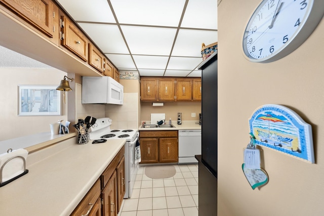 kitchen featuring a drop ceiling, white appliances, sink, tasteful backsplash, and light tile patterned flooring