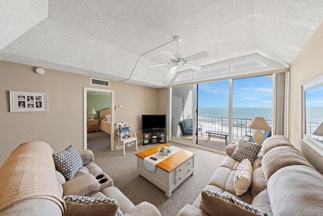 living room featuring carpet, a textured ceiling, vaulted ceiling, and ceiling fan